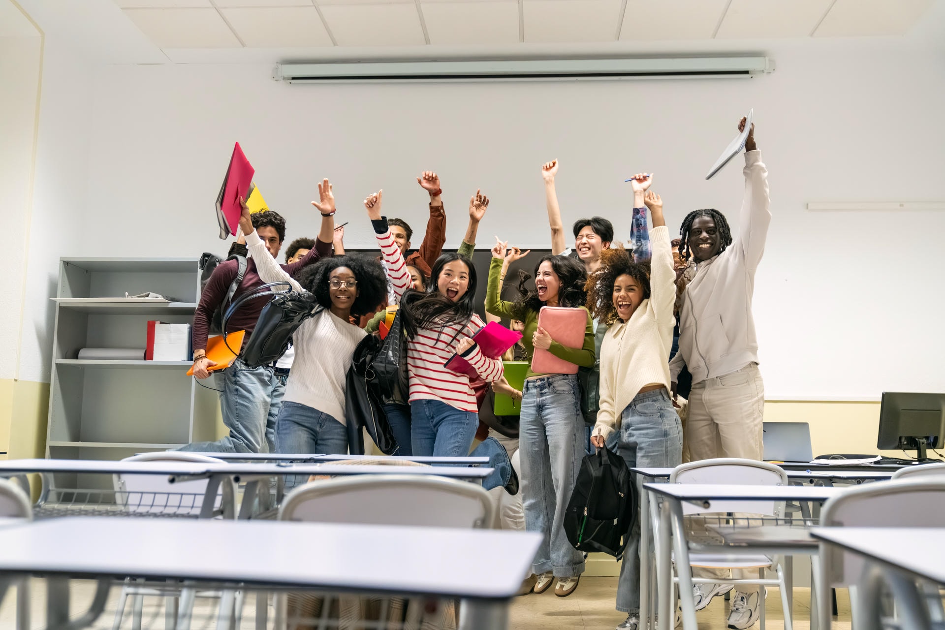 Joyful group of diverse high school or college students jumping and cheering, celebrating a victory or graduation in a classroom SSUCv3H4sIAAAAAAAAE02OPYsCQRBE/0vFHawIwnVubi4GvbN97kA7LfNxIMP898NVwaiK94KqjllKDOCOWWpYk9wUnJoZQZdYPUcx8ESQuEU0a6VmqdHTBrKmRfNW//L+MIGnQfC6PmFH8JZqfoCx+zmAsEop3tIC/hUrSjD3u8ymbzAIQapePUctr1vbv3N/cjCOSwuvdUJpMxgY9JEn9bvpl7kQ5KopPMB9jPEPhZ7krO8AAAA=
